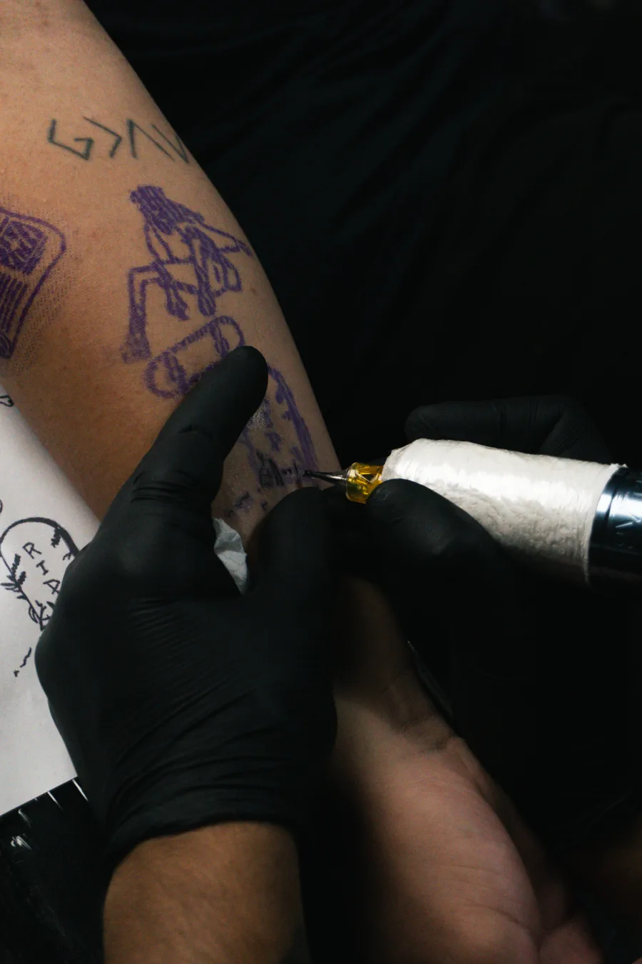 Tatuador trabalhando em tatuagem durante sessão na Lopes Tattoo
