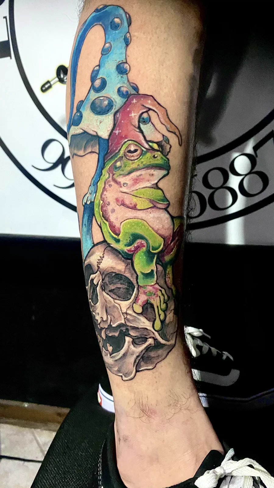 Tatuagem colorida de sapo sobre caveira realizada pela Lopes Tattoo